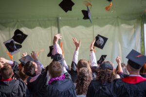 Group of graduates celebrating by tossing caps into the air during a graduation ceremony.